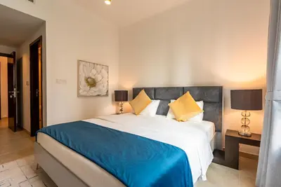 a bedroom with a large bed with blue and yellow pillows at Luxury 2BR Superior Apartment with Full Burj Khalifa and Dubai Mall Dancing Fountain View, Royal Tiffany in Dubai