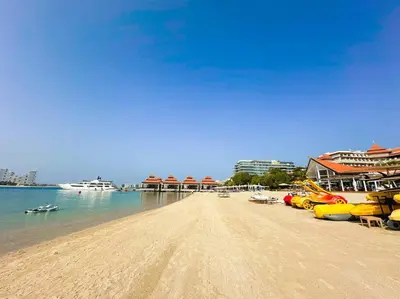 a sandy beach with boats on the water at Palm Apt. with Burj al arab view in Dubai
