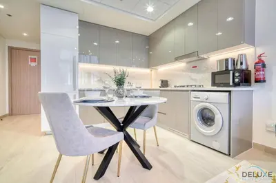 a kitchen with a table and a washing machine at Sizeable 1BR at Azizi Riviera 35, Al Merkadh by Deluxe Holiday Homes in Dubai