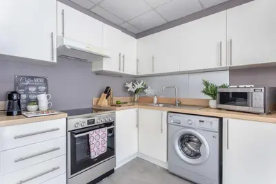 a kitchen with white cabinets and a washer and dryer at Frank Porter - Marina Views Tower B in Dubai