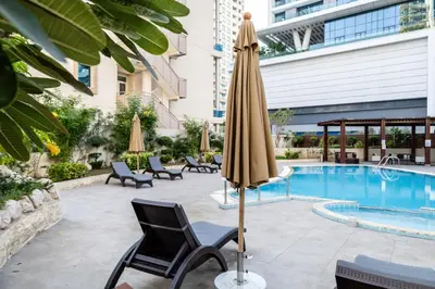 a patio with a umbrella and chairs and a pool at Trophy - Marina Urban Serenity Suite in Dubai