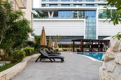 a patio with chairs and umbrellas next to a pool at Trophy - Marina Urban Serenity Suite in Dubai