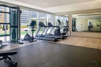 a gym with treadmills and ellipticals in a room with windows at Exclusive Deal, Chic 1BR at a Special Price by Deluxe Holiday Homes in Dubai