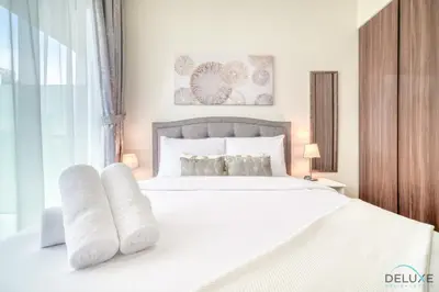 a bedroom with a white bed with white sheets and pillows at Exclusive Deal, Chic 1BR at a Special Price by Deluxe Holiday Homes in Dubai