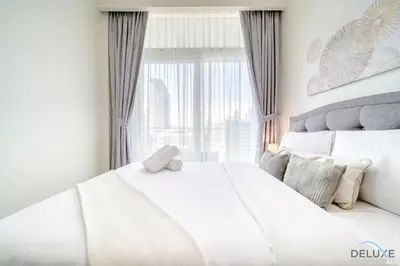 a white bed in a room with a window at Exclusive Deal, Chic 1BR at a Special Price by Deluxe Holiday Homes in Dubai
