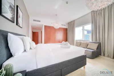 a bedroom with a large white bed and a couch at Colossal 2BR at MAG 218 Dubai Marina by Deluxe Holiday Homes in Dubai