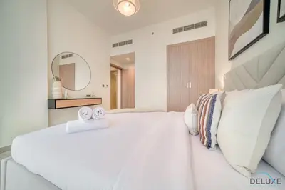 a white bedroom with a large white bed with two towels at Ravishing 2BR at Azizi Riviera 30, Al Merkadh by Deluxe Holiday Homes in Dubai