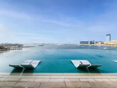 a swimming pool with two chairs in the water at Pleasant 1BD apartment with the beach access in Dubai