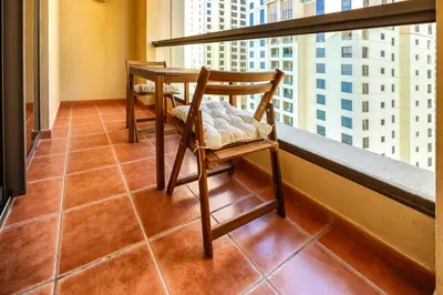 a chair on a balcony with a view of a city at Delightful 2BD apartment near the JBR in Dubai