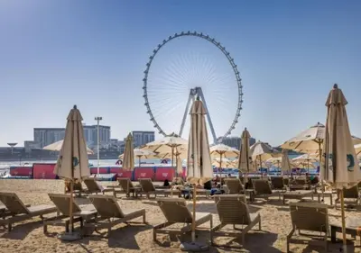 a beach with chairs and a ferris wheel in the background at Delightful 2BD apartment near the JBR in Dubai