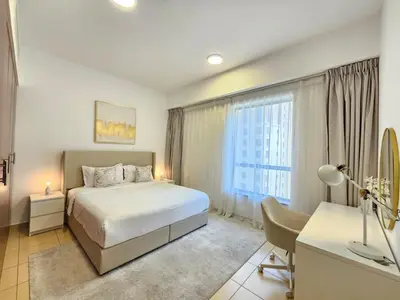 a bedroom with a bed and a desk and a window at Delightful 2BD apartment near the JBR in Dubai