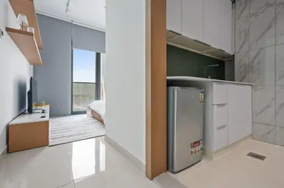 a kitchen with a refrigerator and a bedroom at Studion In Dubailand - Close Kitchen in Dubai