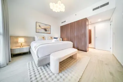 a white bedroom with a large bed and a bench at Luxury Madinat Living 2BR with Sea Views in Dubai
