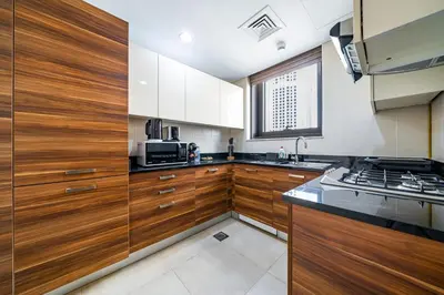 a kitchen with wooden cabinets and a microwave at SettlerHomes - Sparkle Tower 2 with Stunning Views in Dubai