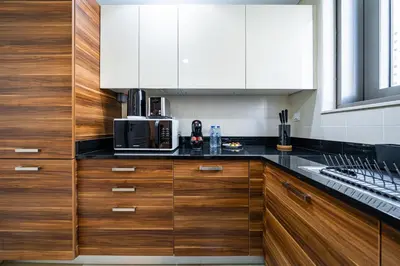a kitchen with wooden cabinets and a microwave at SettlerHomes - Sparkle Tower 2 with Stunning Views in Dubai