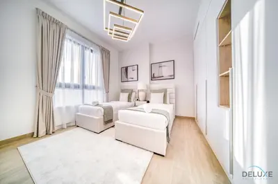 a white bedroom with two beds and a couch at Magnificent 2BR at La Voile Jumeirah by Deluxe Holiday Homes in Dubai