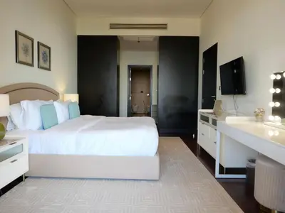 a bedroom with a large white bed and a sink at Elegant 1BR Full Palm View Apartment at 5 Star Resort in Dubai