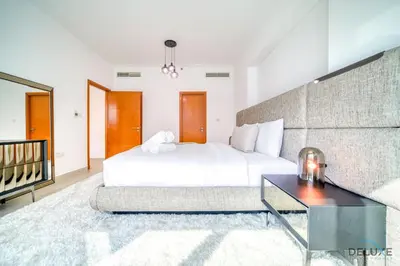 a bedroom with a white bed and a table at Elegant 2BR at Beauport XI Dubai Marina by Deluxe Holiday Homes in Dubai