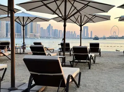 a group of chairs and umbrellas on a beach at Seaside 1BR Getaway - Seven Palm in Dubai