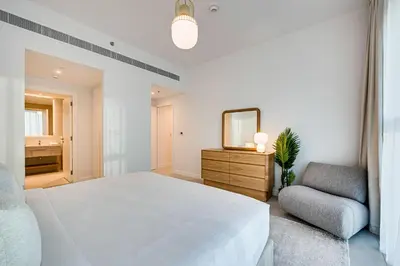 a bedroom with a large white bed and a chair at Panoramic sea view from new 2BD in La Vie JBR in Dubai