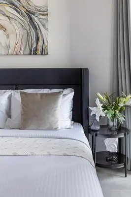 a bed with a black headboard and a table with flowers at Frank Porter - 15 Northside in Dubai