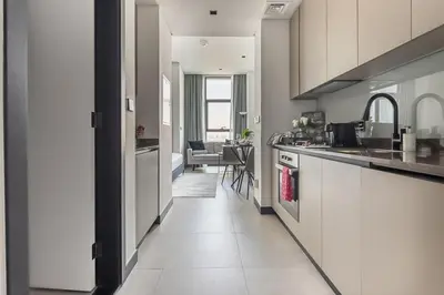 a kitchen with white cabinets and a living room at Frank Porter - 15 Northside in Dubai