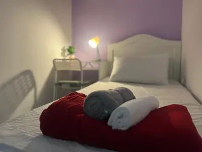 a bed with a red blanket and towels on it at Seperate Partition Room in Tecom / Barsha Heights in Dubai