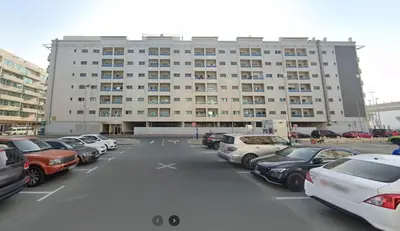 a parking lot with cars parked in front of a building at Fancy Partition Room Near Mashreq Metro / SZ Road in Dubai