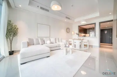 a white living room with a white couch and a table at Plush 2BR at Grand Opera Downtown Dubai by Deluxe Holiday Homes in Dubai