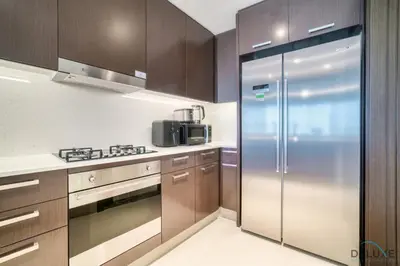 a kitchen with a stainless steel refrigerator and wooden cabinets at Plush 2BR at Grand Opera Downtown Dubai by Deluxe Holiday Homes in Dubai