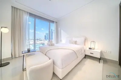 a white bedroom with a large bed and a large window at Plush 2BR at Grand Opera Downtown Dubai by Deluxe Holiday Homes in Dubai