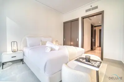 a white bedroom with a white bed and a table at Plush 2BR at Grand Opera Downtown Dubai by Deluxe Holiday Homes in Dubai