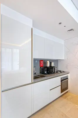 a white kitchen with white cabinets and a microwave at Luxurious Flat 3 Min to Burj Khalifa Sleeps 3 in Dubai