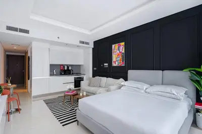 a bedroom with a white bed and a living room at Luxurious Flat 3 Min to Burj Khalifa Sleeps 3 in Dubai