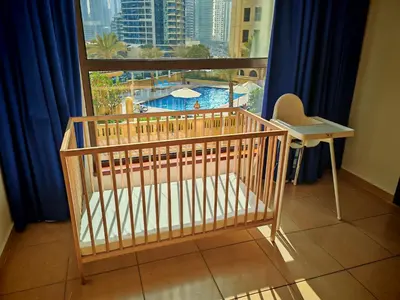 a crib in front of a window with a view of a pool at Spacious 2BR Apt on JBR Beach near Mall & Metro By La Buena Vida Holiday Homes in Dubai