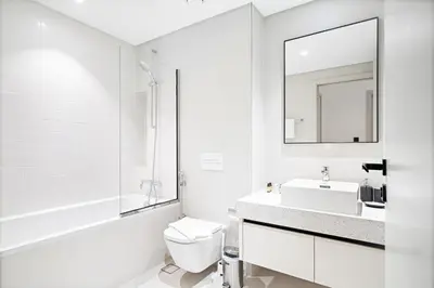 a white bathroom with a sink and a mirror at Silkhaus Sea View 1BDR in Marina Vista, near Marina in Dubai