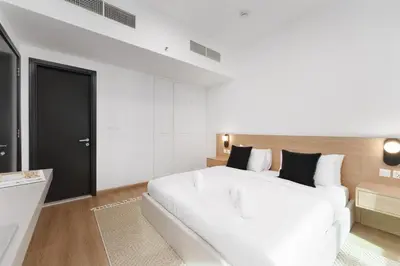 a white bedroom with a white bed and a black door at Luxe Living in our Exquisite 1 Bedroom Apartment in Dubai