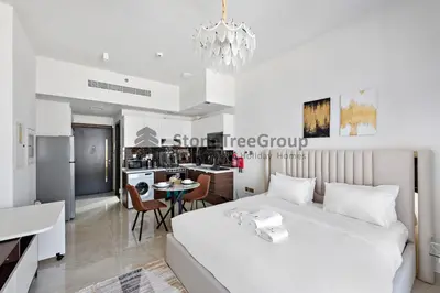 a bedroom with a white bed and a kitchen at StoneTree - Brand New Studio in Jewelz Residence in Dubai