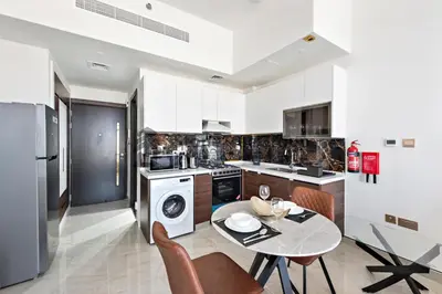 a kitchen with a table and a kitchen with a washer at StoneTree - Brand New Studio in Jewelz Residence in Dubai
