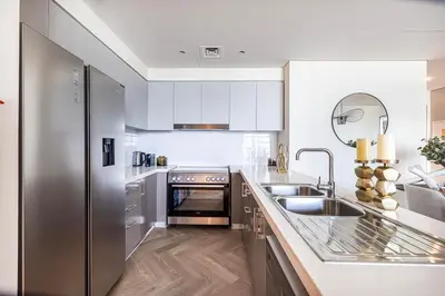 a kitchen with white cabinets and a stainless steel refrigerator at Daniels Luxury 3BR with Dubai Opera Views in Dubai