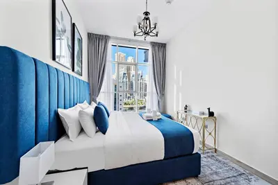 a bedroom with a blue and white bed and a window at StoneTree - Elegant 1BR with Stunning View of Marina in Dubai