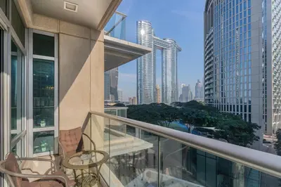 a balcony with chairs and tables and a view of a city at Close to Metro - Classic 2BR in Loft East,Downtown in Dubai
