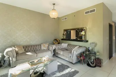 a living room with two couches and a mirror at Close to Metro - Classic 2BR in Loft East,Downtown in Dubai