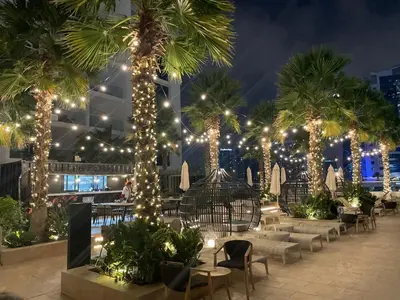 a patio with palm trees with lights and chairs at Damac Prive l Canal View l Great Location in Dubai