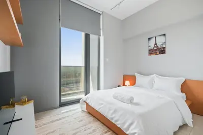 a bedroom with a white bed and a large window at Sunny Studio In Vibrant Dubailand Area in Dubai