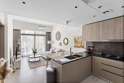 a kitchen and living room with a sink and a couch at Cosy 1BR in the center of JVC in Dubai