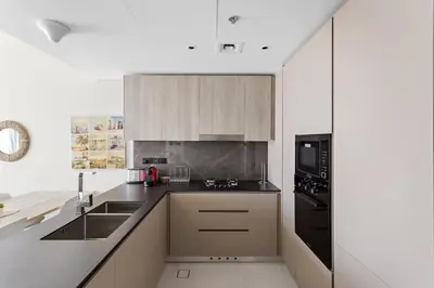 a kitchen with white cabinets and black appliances at Cosy 1BR in the center of JVC in Dubai