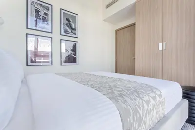 a bedroom with a white bed with pictures on the wall at Frank Porter - Riviera 27 in Dubai