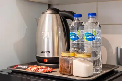 a tea kettle and two bottles of water and spices at Modern JLT Studio Lake View 5min MetroMarina in Dubai