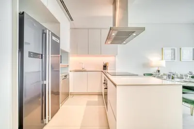 a kitchen with white cabinets and a stainless steel refrigerator at Address JBR Marina View, JBR, Dubai Marina - Mint Stay in Dubai